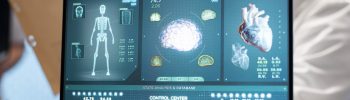 Laptop displaying AI-powered diagnostic dashboard with brain, heart, and skeletal analysis in a healthcare compliance environment